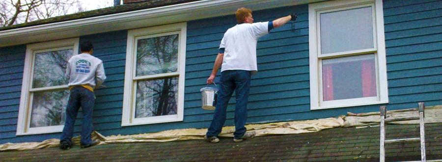 men painting a house blue