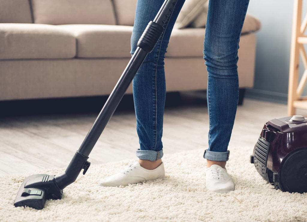 a woman vacuuming a white rug