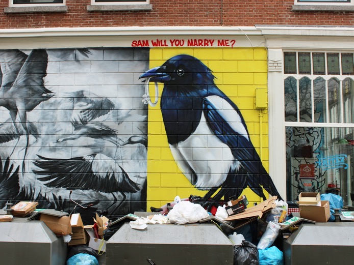 dumpsters along a painted wall