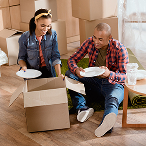 couple packing dishes into a cardboard box