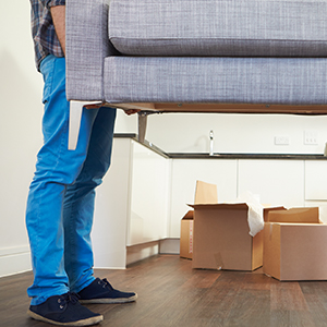 man with blue jeans lifting a couch