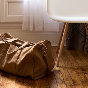 brown duffel bag sitting on the floor next to a white chair