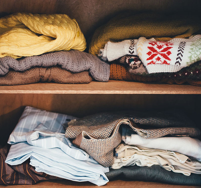 clothes stacked on a closet shelf