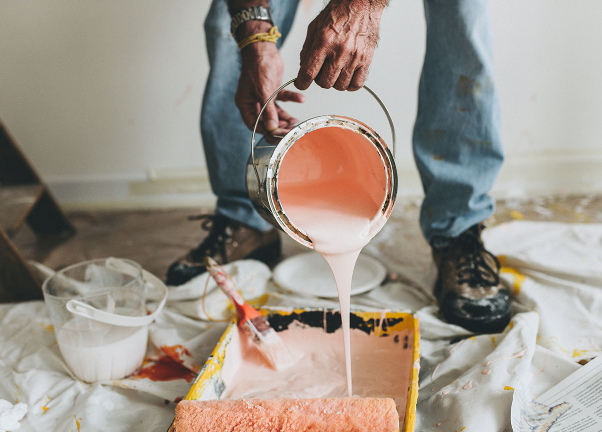 man pouring pink paint into a pan