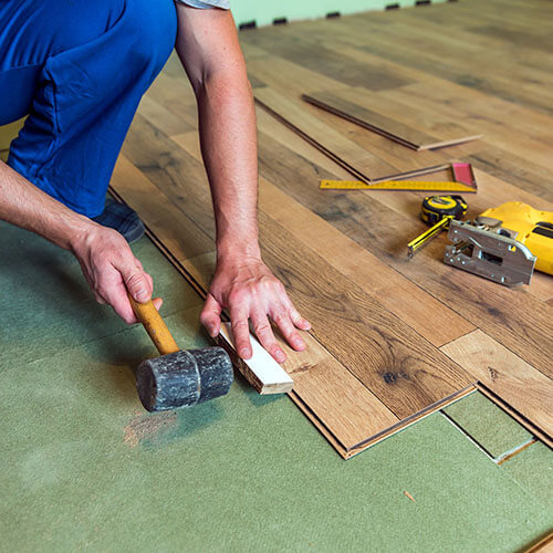 man with a mallet installing flooring