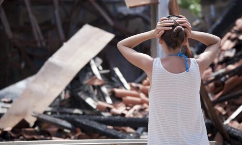 tenant standing in front of a burned down house