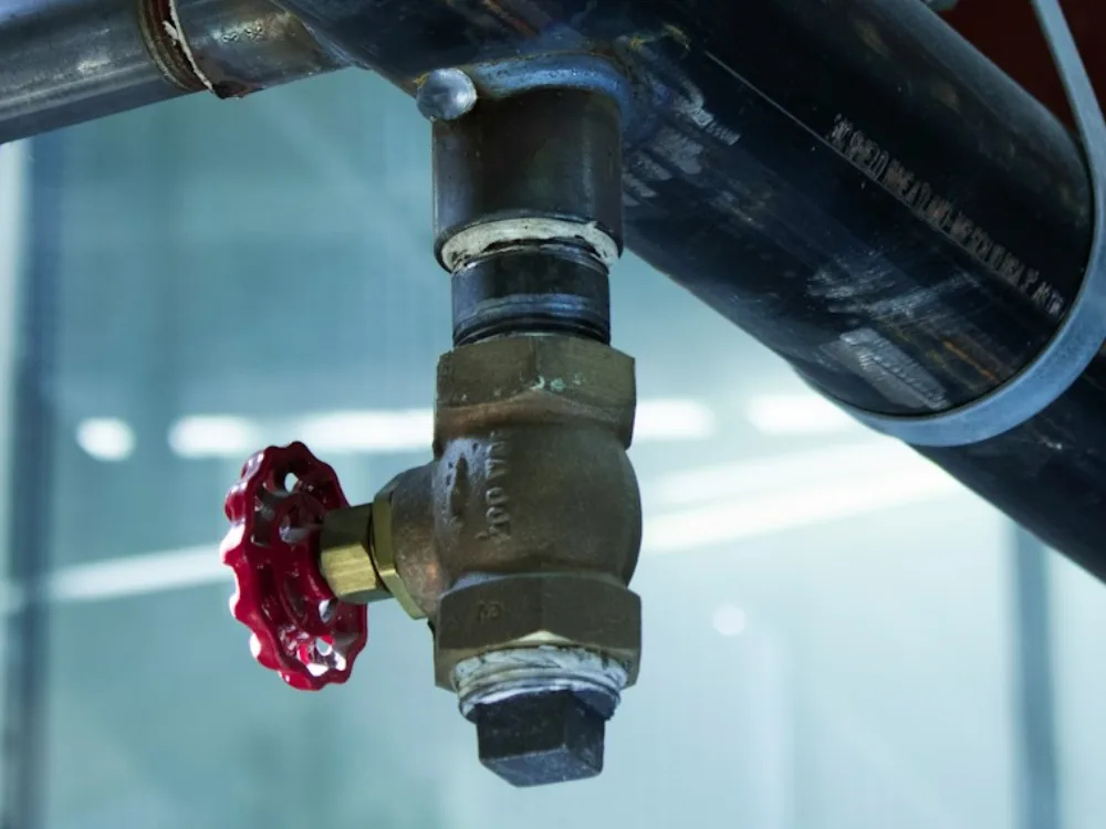 A main water shutoff valve with a red handwheel