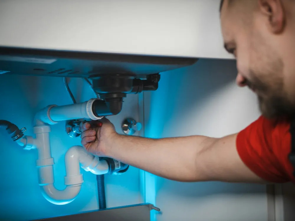 A Pro working on the drain trap under a sink
